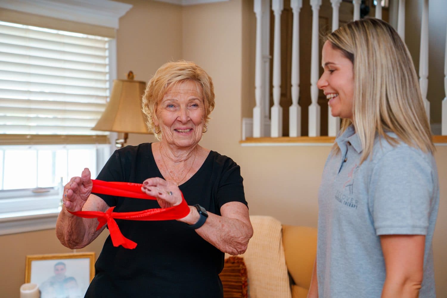 Older adult facing forward while practicing a home resistance band exercise with Nicole.