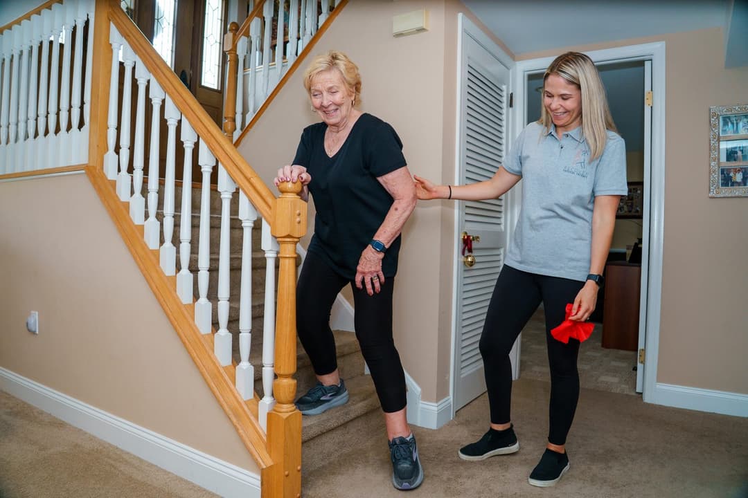 Nicole supporting an older adult practicing stairs at home.